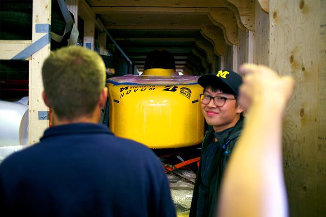 A yellow vehicle in a large wooden crate.
