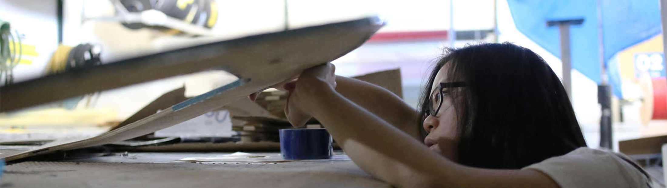 A girl working on a carbon fiber sheet on a workbench.
