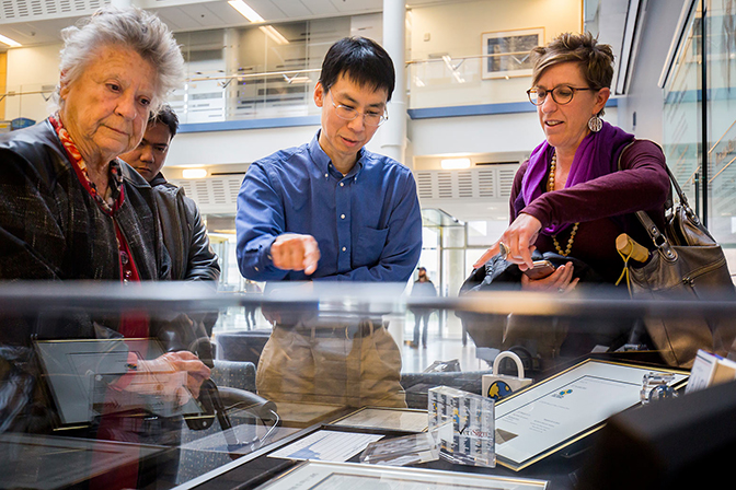 People looking at something displayed in a glass case.