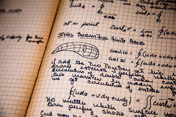 A closeup of a graph paper notebook with diagrams and words written in it.