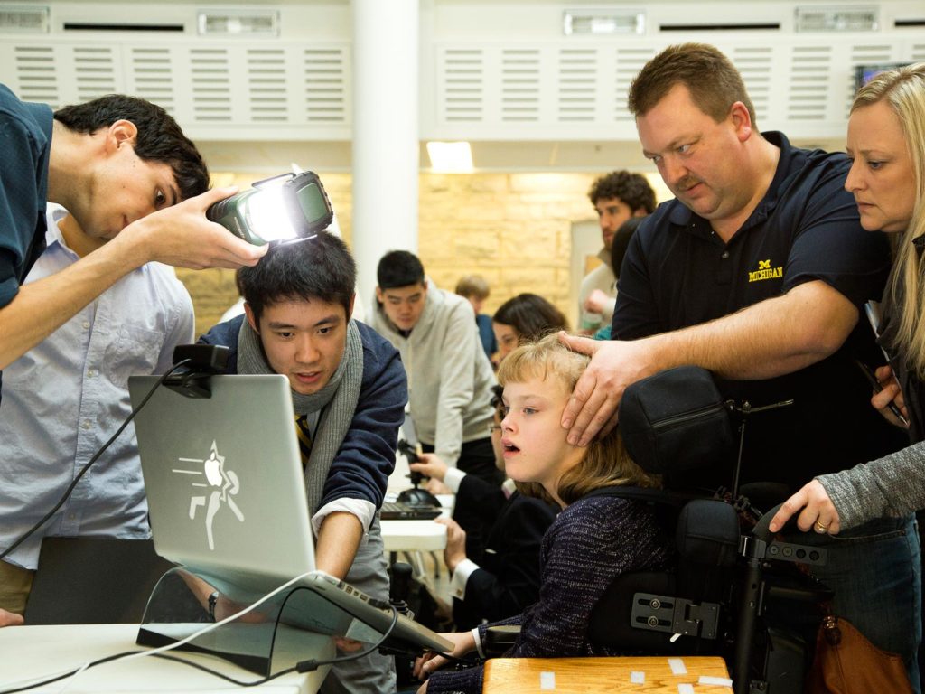 students assist teenager with testing assistive gear
