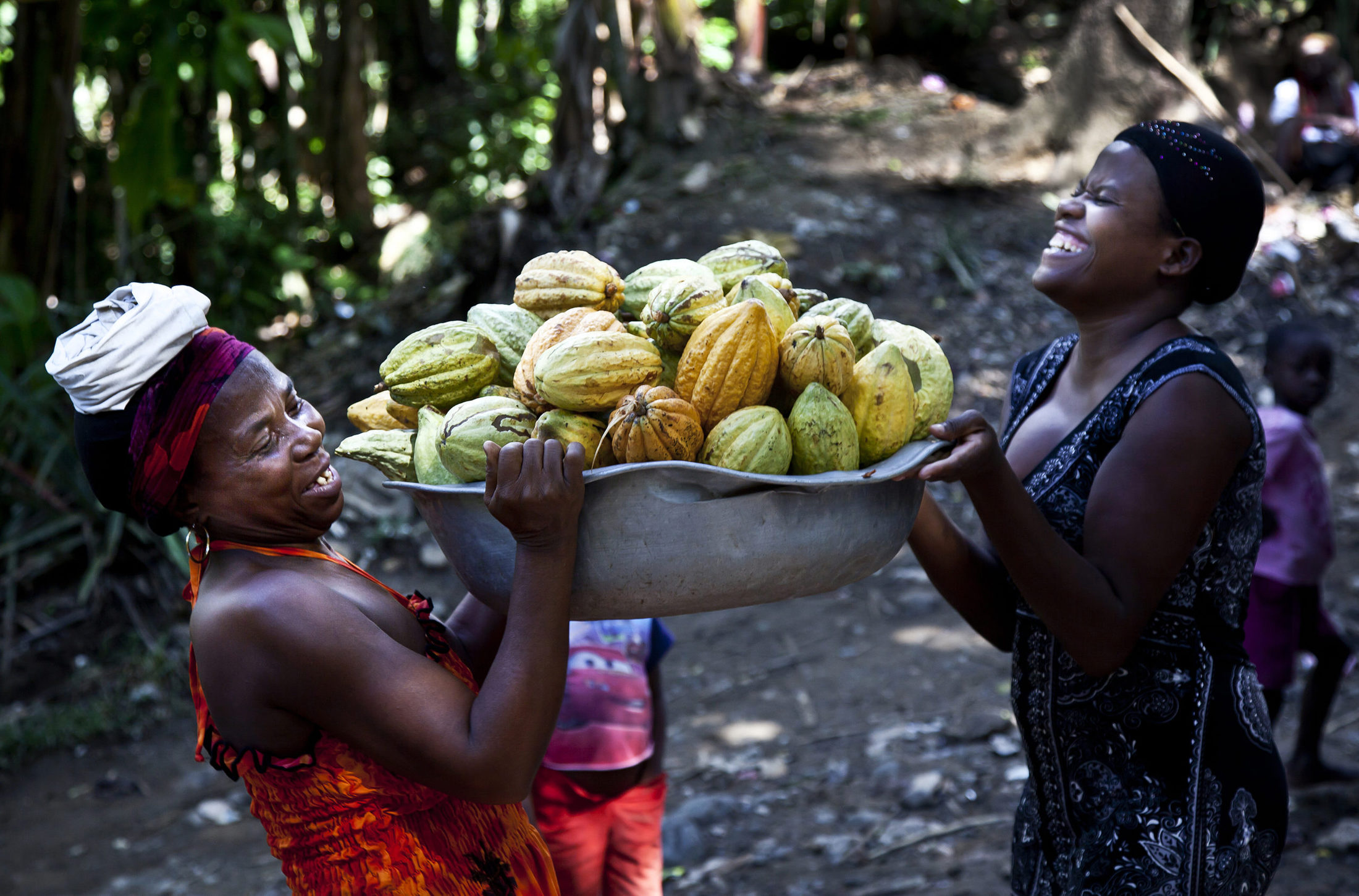Two women holding a basket of cacao.