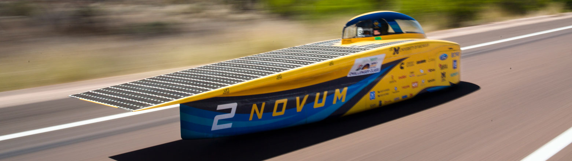 A small vehicle with a solar panel speeds along a track.