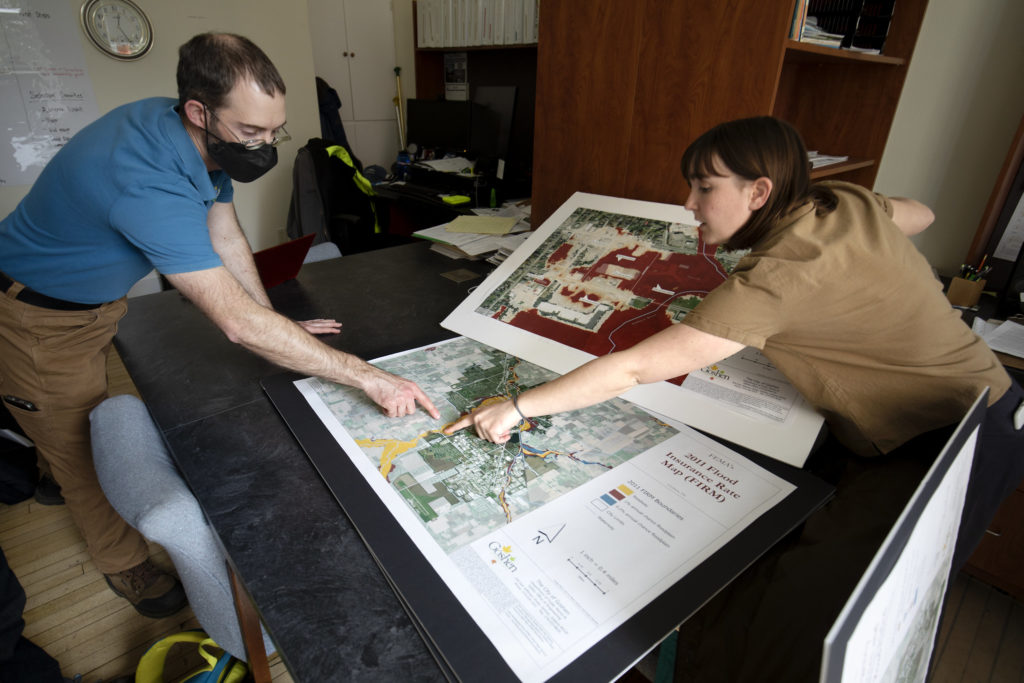 Two people stand over a map and point to areas of need