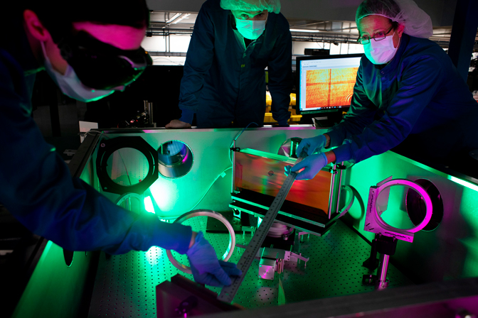 Three people measuring instruments over the laser