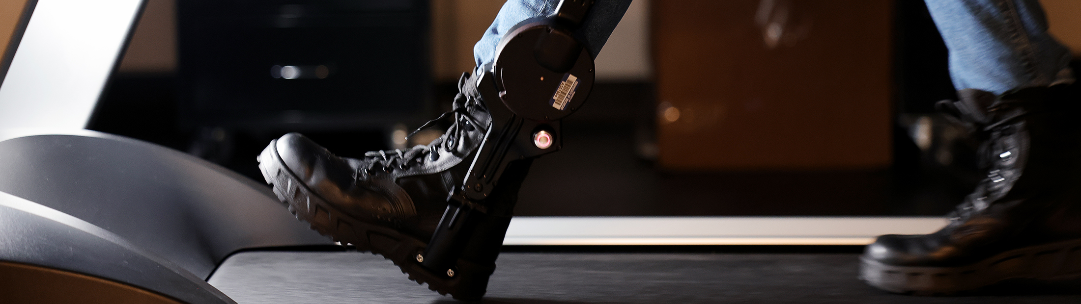 An ankle exoskeleton strapped to a human walking on a treadmill