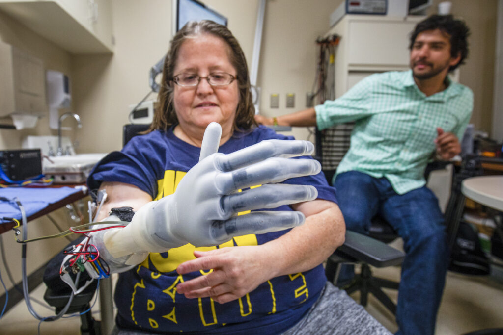 Research participant Karen Sussex performs tests using a computer-operated hand in the lab. 