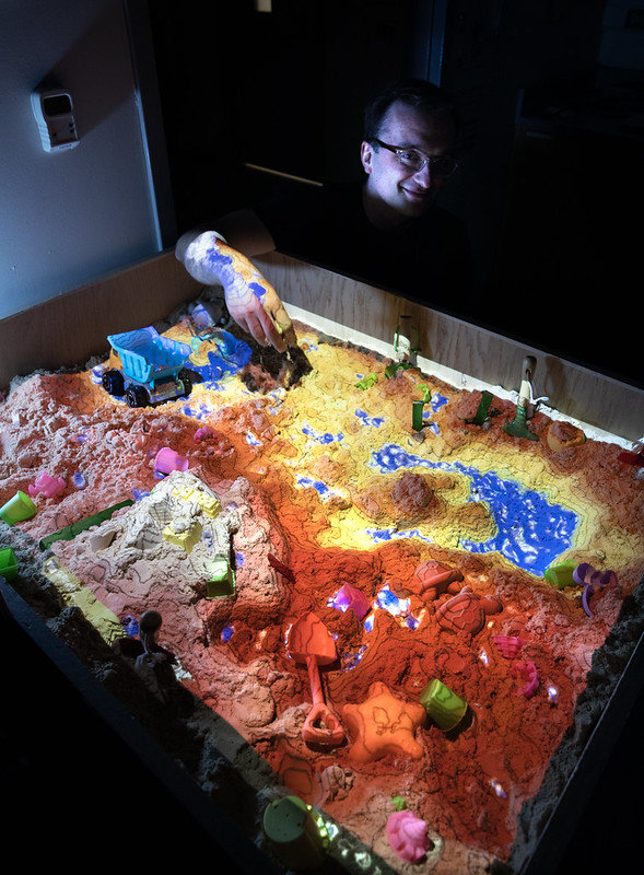 Kerkez with an Augmented Reality Sandbox in his lab. The sandbox allows users to digitally change the physical topography and hydrology of the space to better understand interactions to changes in the environment. Photo: Marcin Szczepanski/Michigan Engineering