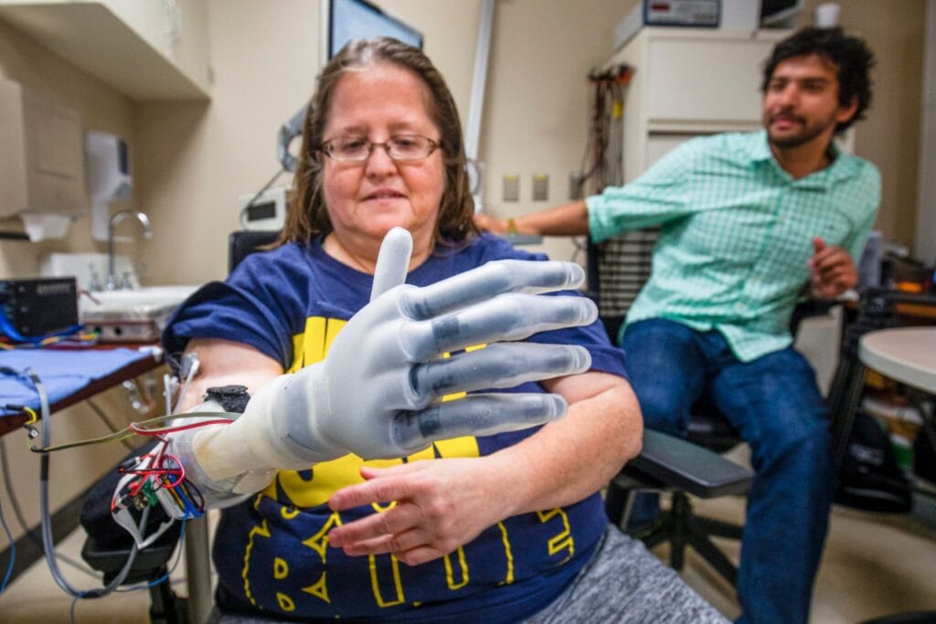 Research participant Karen Sussex performs tests using a computer-operated hand in the lab. 
