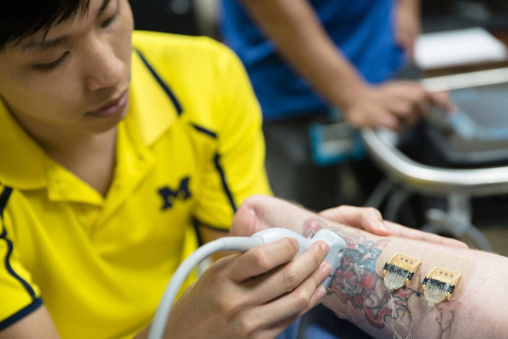 A researcher uses an ultrasound wand on a research participant's arm. 