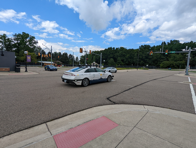 Three cars at a four-way intersection with stoplights