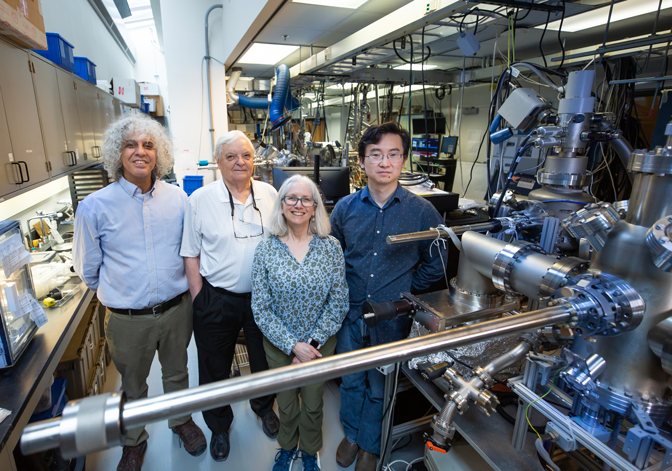 Four researcher standing in a lab with their equipment behind them