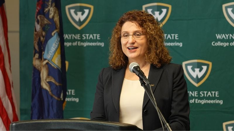 Valeria Bertacco stands at a podium in front of a Wayne State backdrop