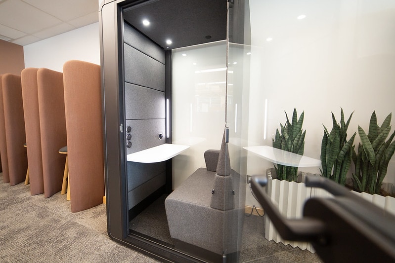 A small pod with room for one. There's a small white desk space inside and a glass slider door.