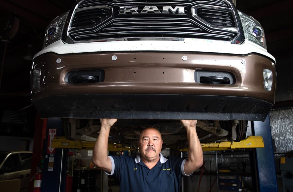 A man standing under a lifted RAM truck