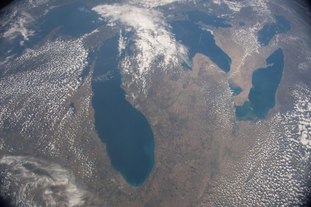 A satellite image looking down on the Midwest. The state of Michigan can be seen easily, with all five Great Lakes in view. There's scattered cloud cover.