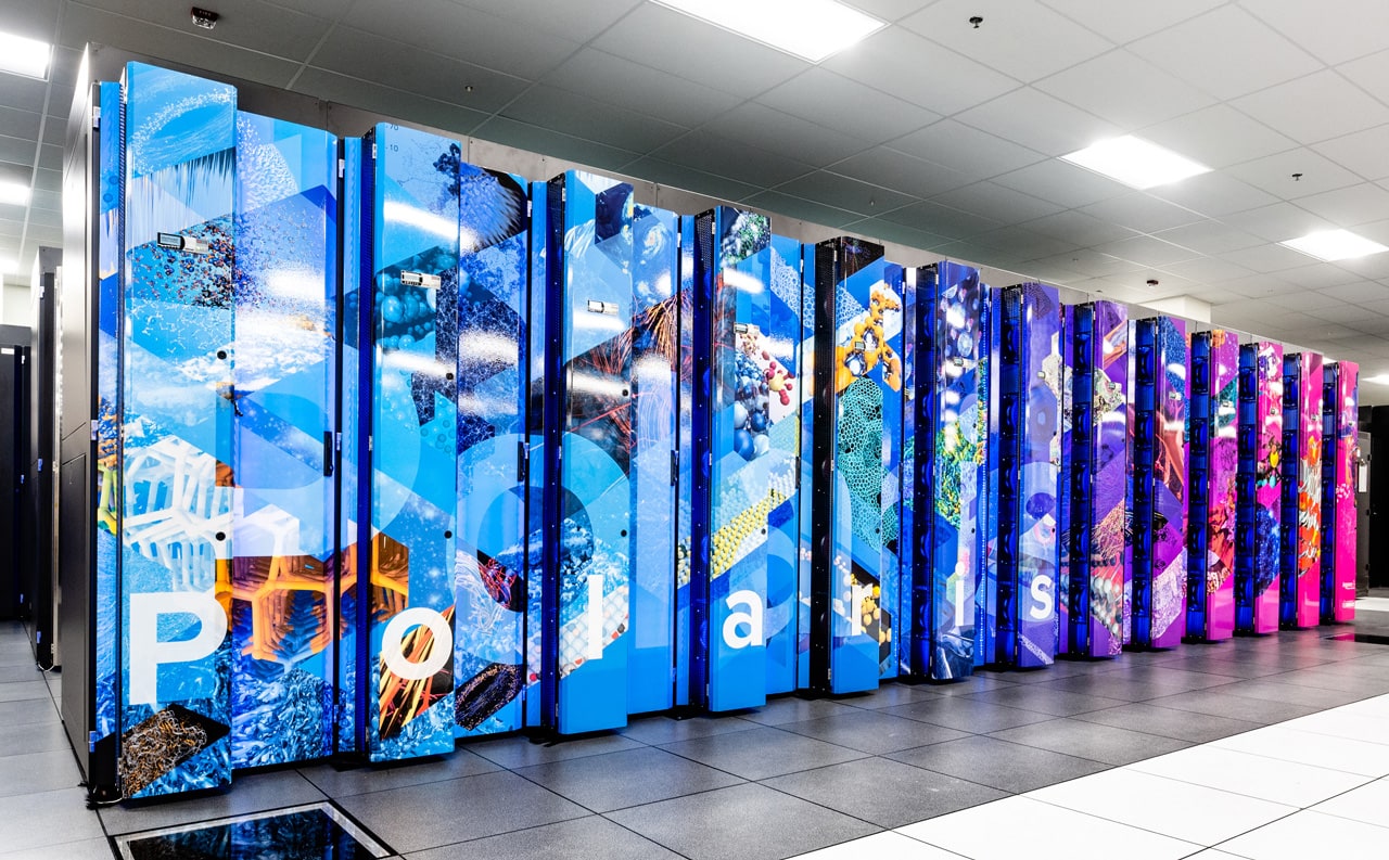 Black computer racks in a room with a tile floor and drop ceiling. The front of the first rack is colorfully painted with representations of molecules, structures and more.