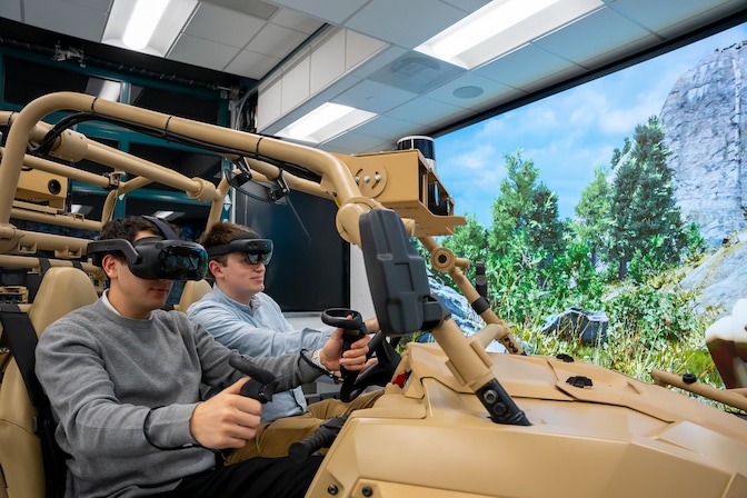 Two students sit in a military vehicle simulation developed by researchers and students inside the University of Michigan-led Automotive Research Center (ARC).