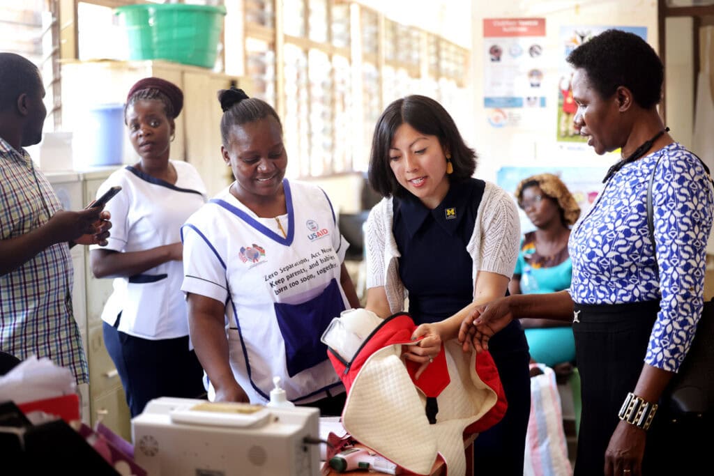 Grace Hsia-Haberl stands in a group of nurses and other hospital staff to demonstrate how to use the IncuBlanket . 