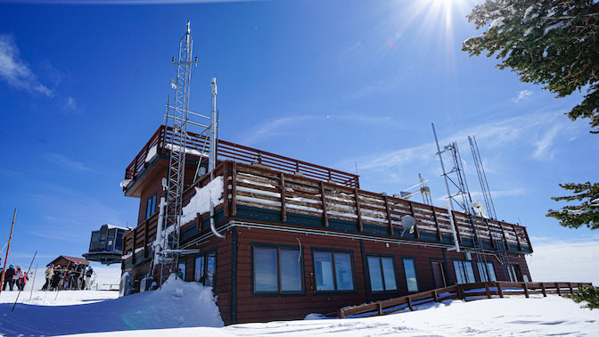 The outside of storm peak lab resembles a cabin at a ski resort, except it has several metal radio towers with instruments that collect data on the properties of clouds and snow. 