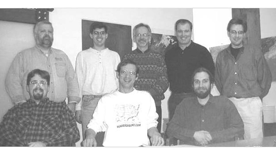 Black and white photograph of eight men posing. Jeff Masters is front and center with a white shirt with a map of the U.S. and "Wunderground.com" printed on it.