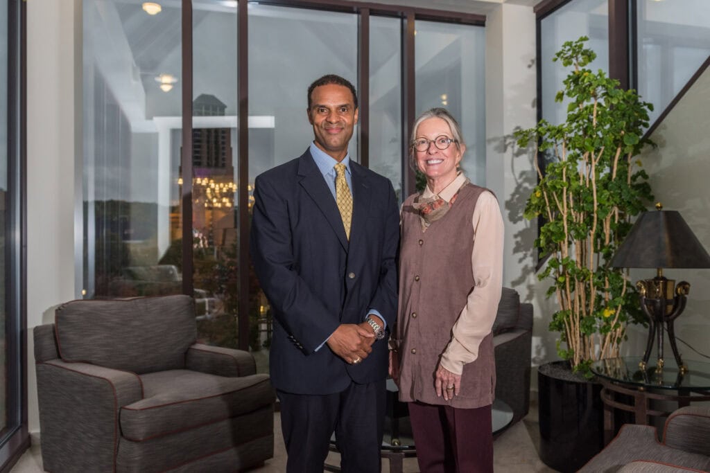 Ann and Alec stand in front of a window, smiling. In the background, Lurie Tower can be seen