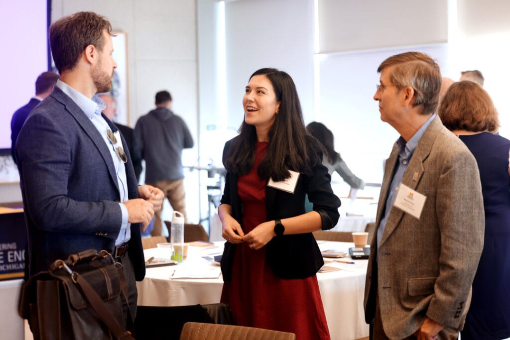 Three people stand in conversation at the MISA symposium. 