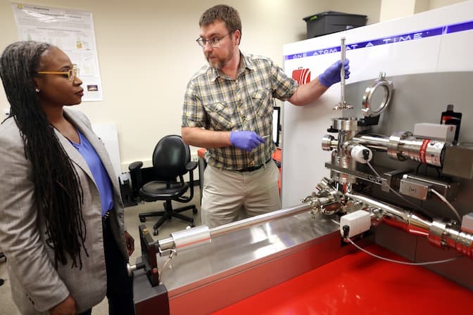 Hunter opens a chamber on the 3D atom probe while Eniola-Adefeso observes.