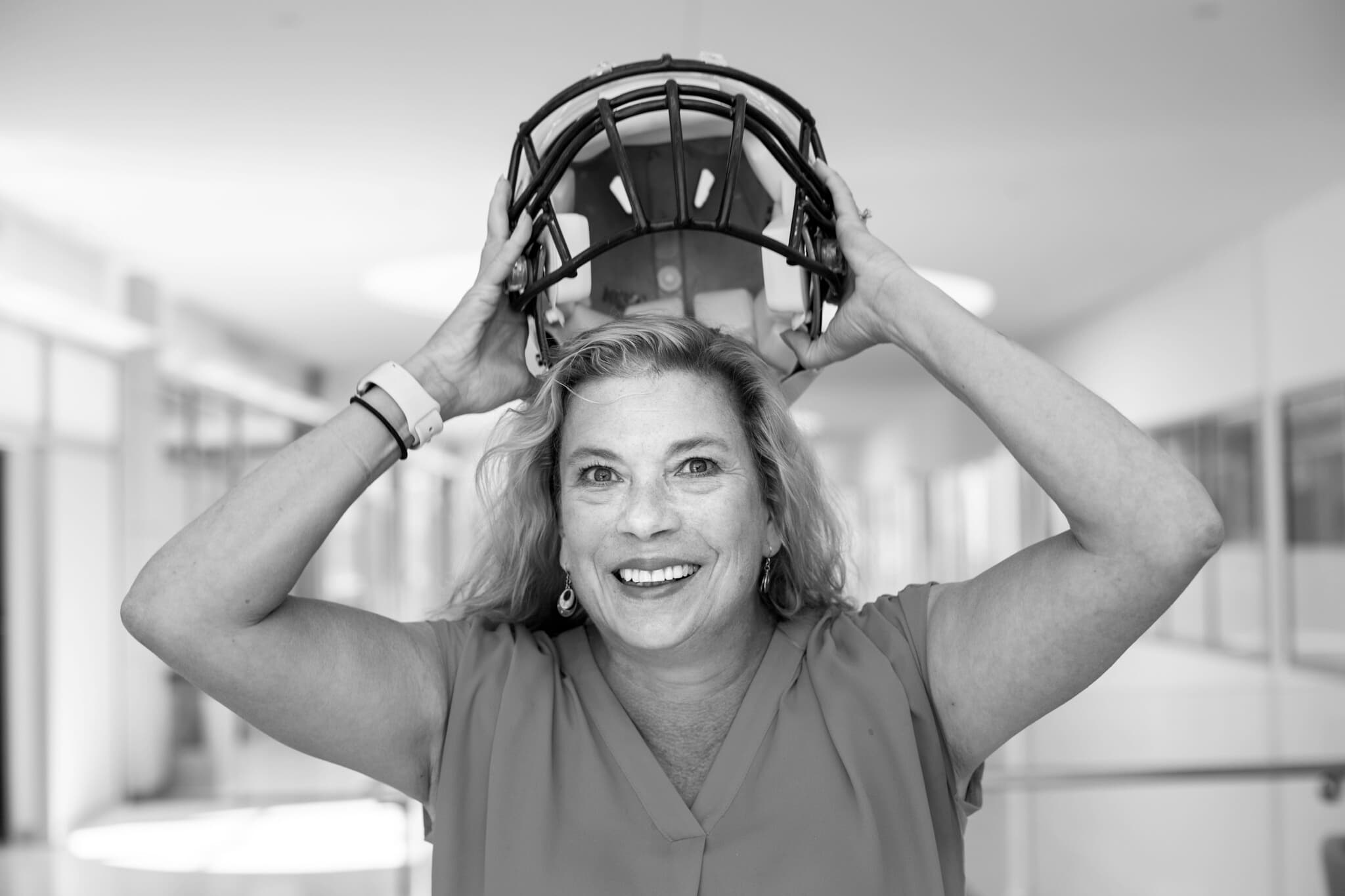Ellen Arruda stands for a portrait. She is posing with a U-M football helmet, as if she's just taken it off her head.