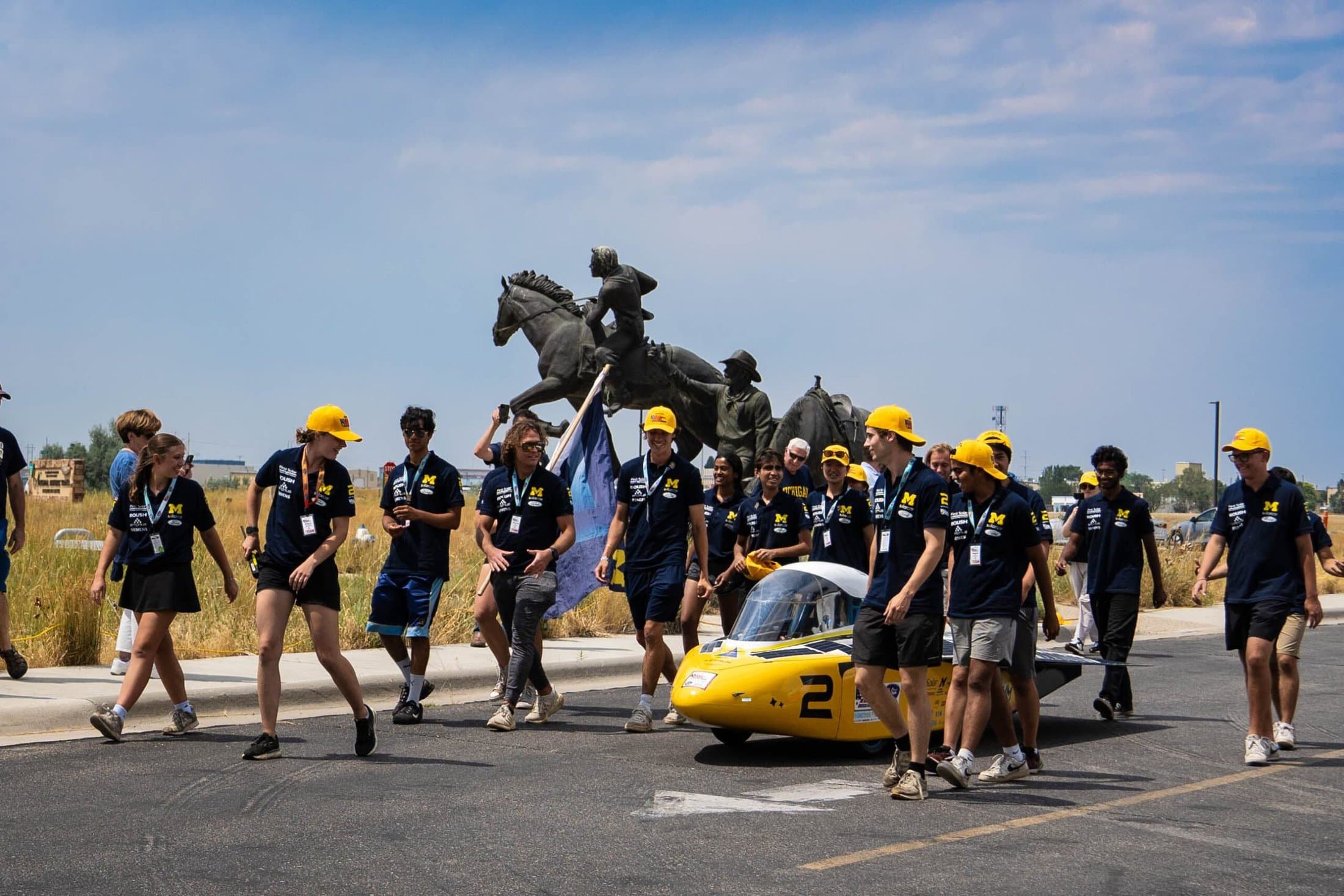 College students surround the solar car they built as it crosses the finish line of a race.