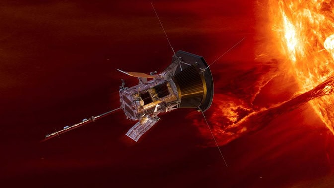 Parker looks like a cylindrical probe with panels and antenna protruding from a few faces. One of its flat faces points toward the sun as it flies past the glowing yellow-orange fireball.