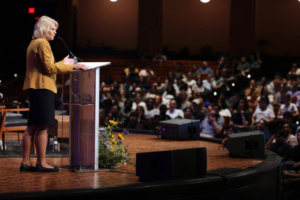 Dean Karen A. Thole stands at a podium addressing the fireside chat crowd. She's wearing a yellow suit jacket and a black skirt.