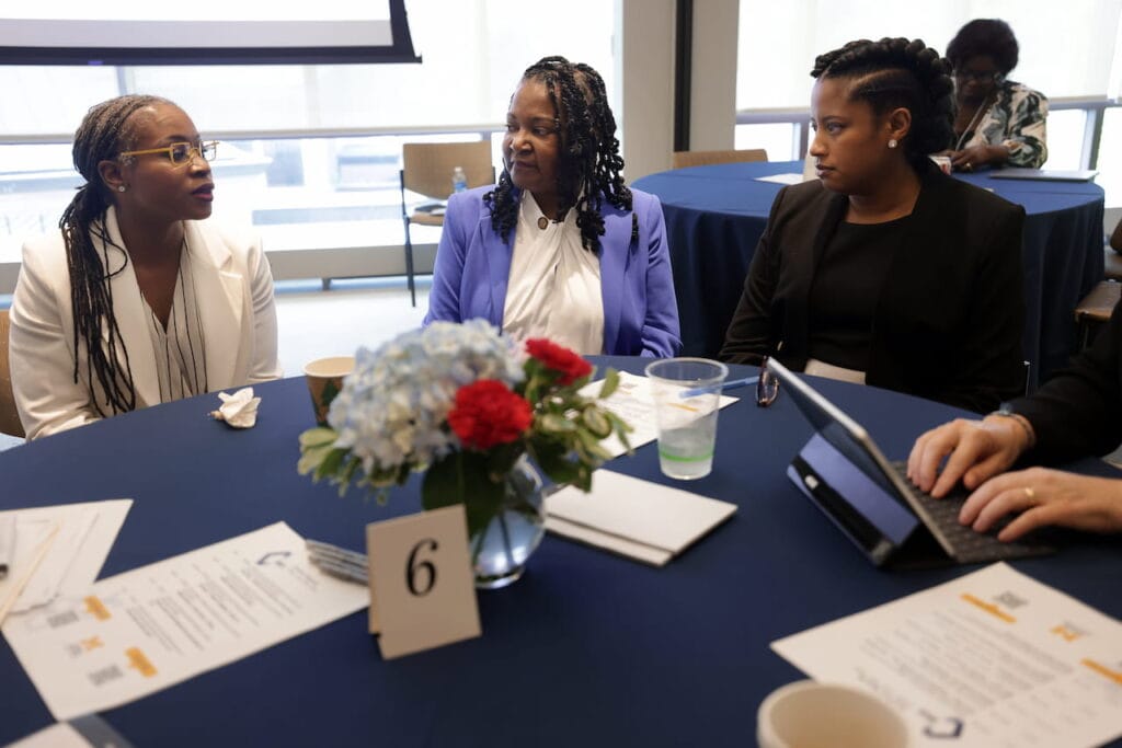 Three people sit at a table in discussion