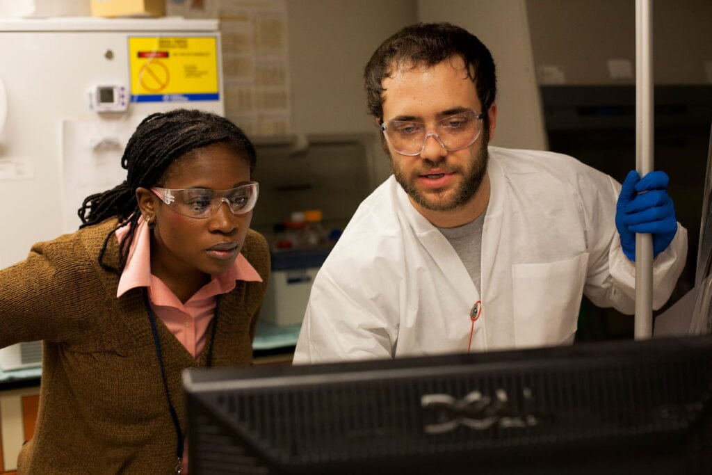 Two researchers looking over computer screens at results