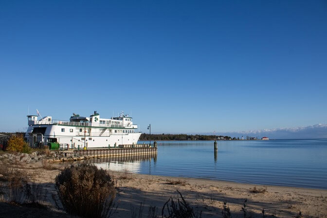 The bow of the Emerald Isle, which is parked at a dock, points toward the open blue waters of Lake Michigan.