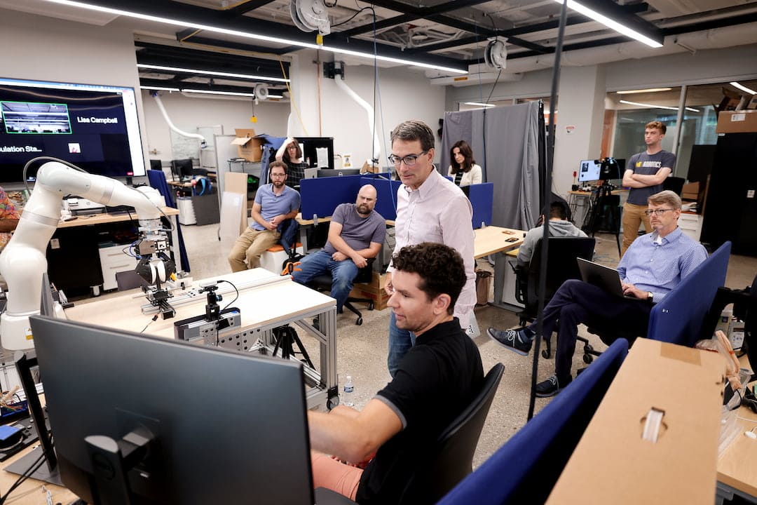 Eric Krotkov, advisor for the University Research Program at Toyota Research Institute (TRI), center, is given a project update in the lab of professors Dmitry Berenson and Nima Fazeli in the Ford Motor Company Robotics Building.