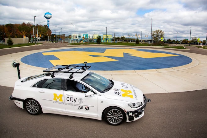 An Mcity vehicle with sensors around the frame of the car idles in a roundabout inside Mcity