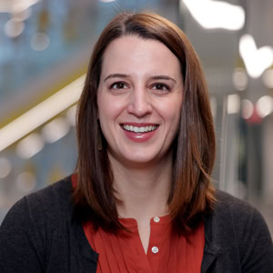 Portrait photograph of Patricia Delacy. She is wearing red shirt and a grey cardigan. 