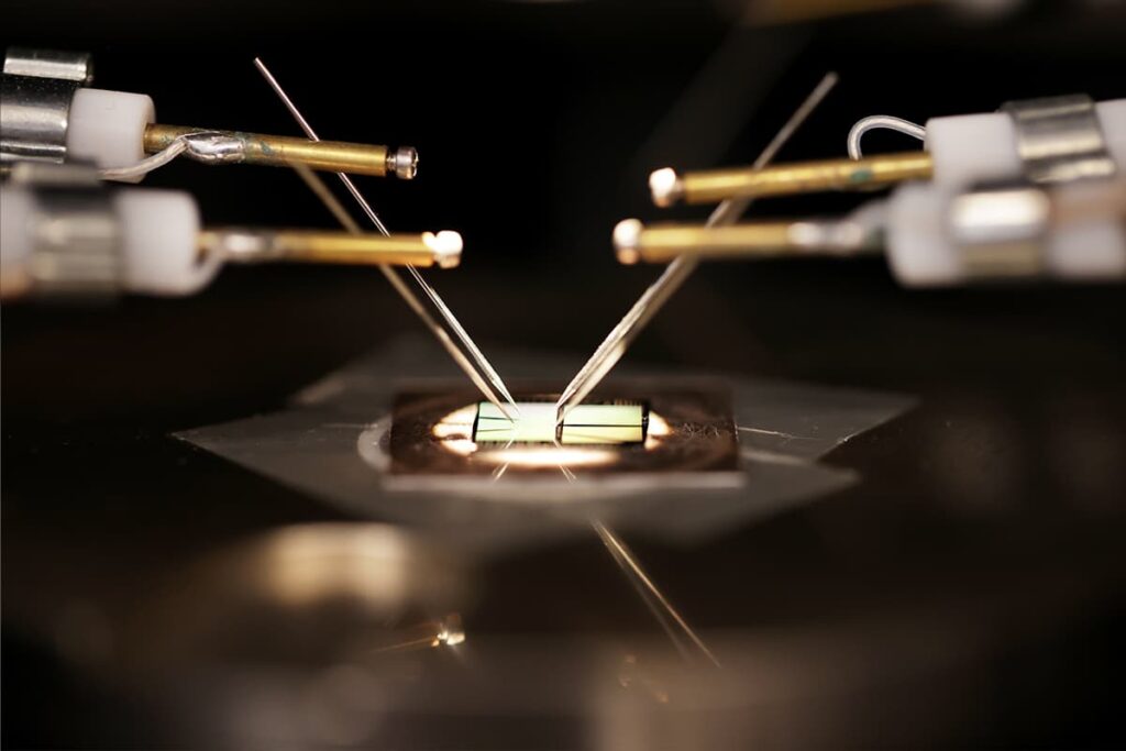 A microchip is being probed by fine metal needles in a laboratory setup.