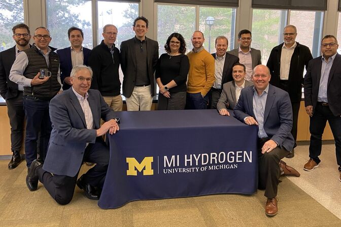 Members of the MI Hydrogen Advisory Board gathered around a table with a MI Hydrogen logo on a tablecloth.