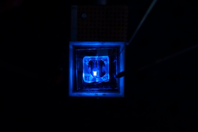 A rectangular blue light shines from a transparent square, its edges marked out by the glow.