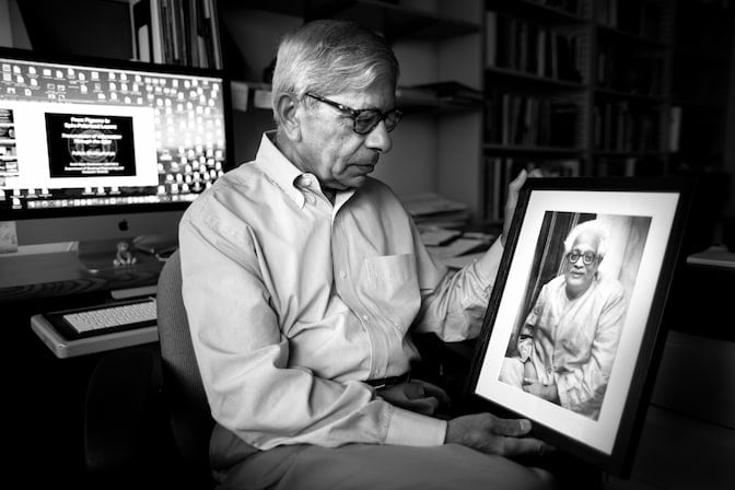 Pallab Bhattacharya seated looking at a photo.