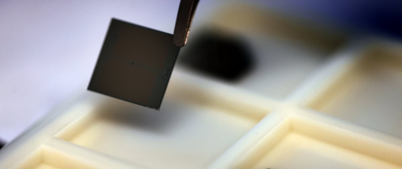 A black square about the size of a postage stamp is held over a cream-colored tray with inset areas.
