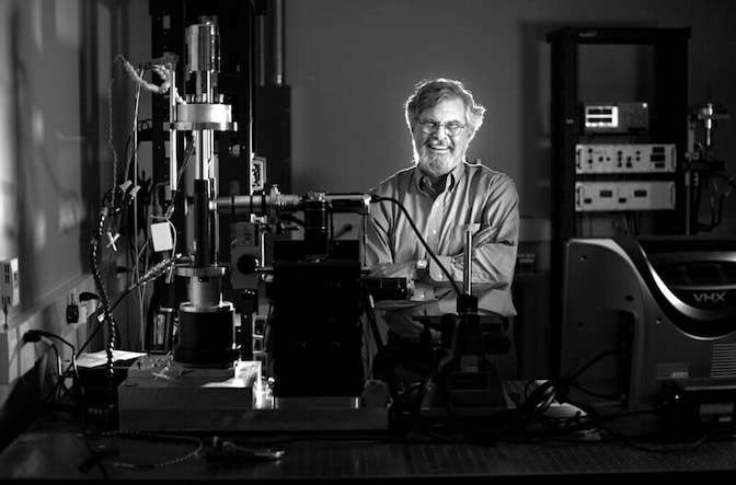 Portrait of John Allison next to lab equipment. 