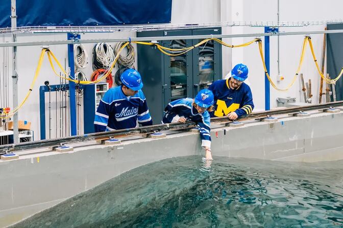 Researchers collect a water sample from a indoor water tank.
