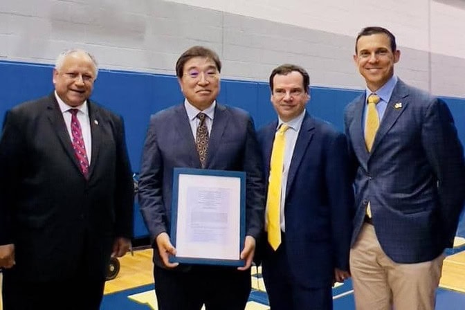 Four men stand together hold a Memorandum of Understanding (MoU) which outlines a collaborative effort aimed to cultivate U.S. shipbuilding expertise through specialized training program.