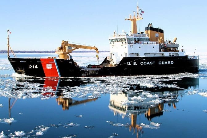 U.S. Coast Guard icebreaker ship navigating icy waters with "214" and "U.S. COAST GUARD" on its hull.