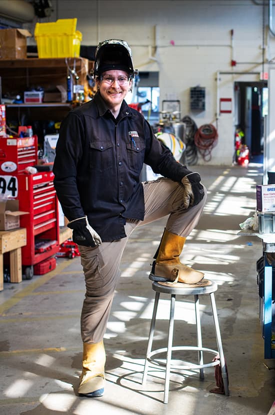 Portrait of Blake DesRosiers wearing welding safety equipment in the lab.