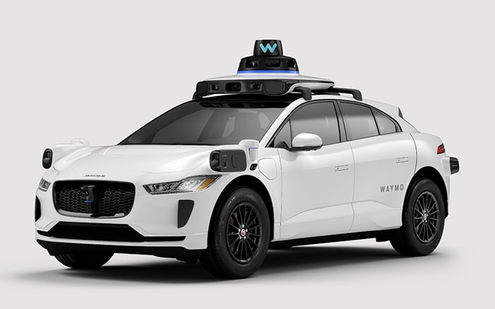 A white sedan with round layers of equipment on its roof on a gray background.