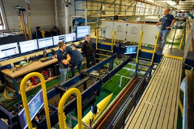 Four researchers in a marine lab room with computers and industrial machinery.